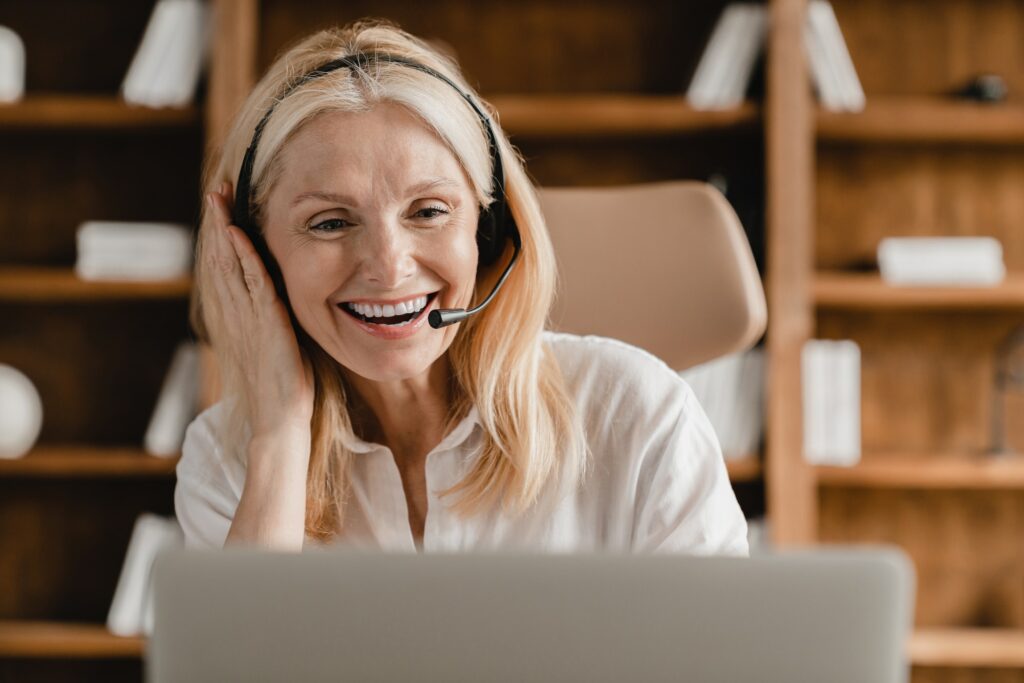 IT support agent, secretary wearing headset while talking helping clients using laptop in office.