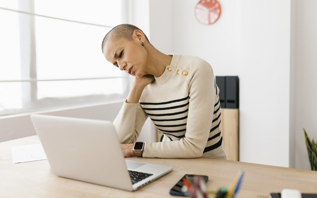 Mid adult woman suffering from neck pain working on laptop at home office