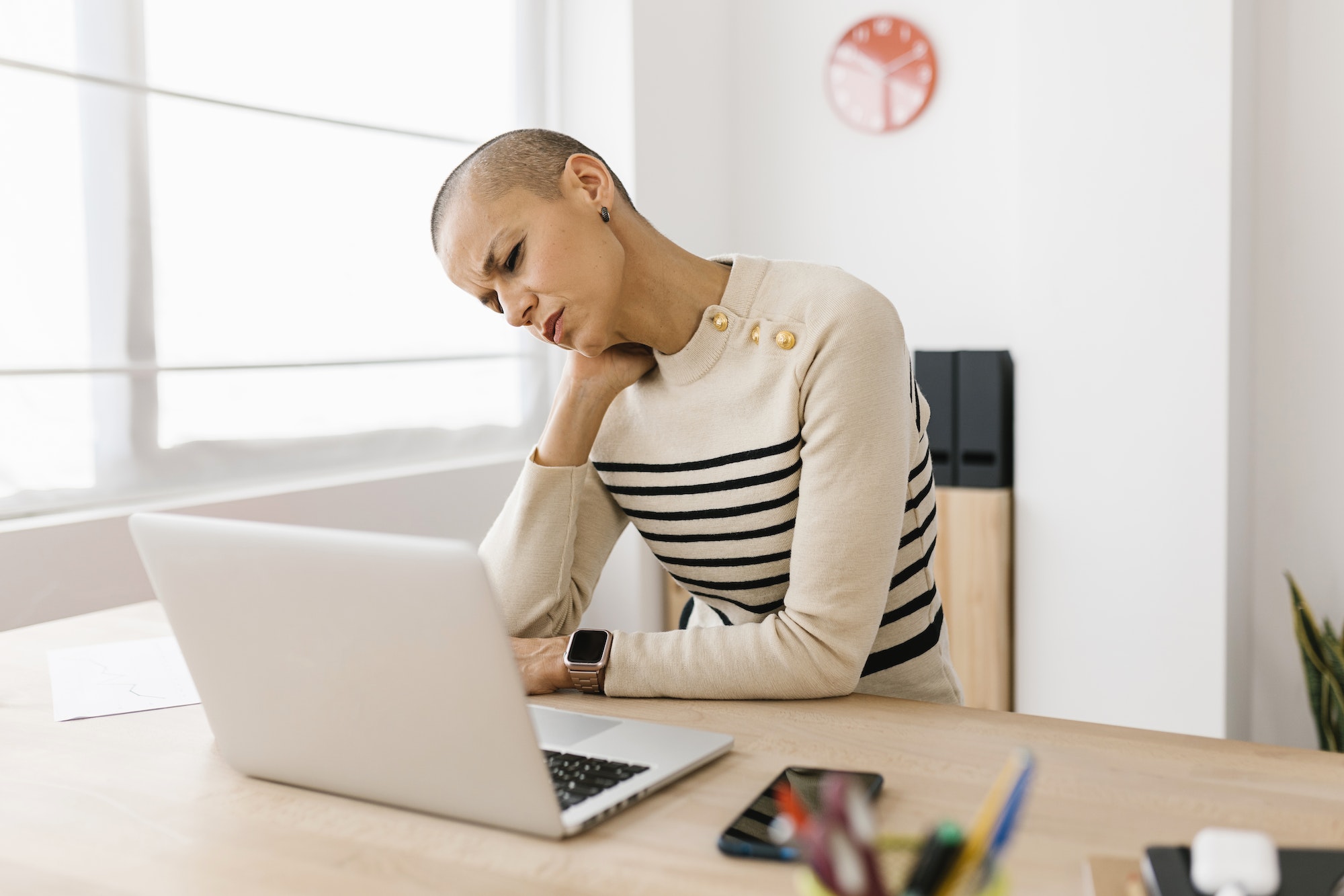 Mid adult woman suffering from neck pain working on laptop at home office