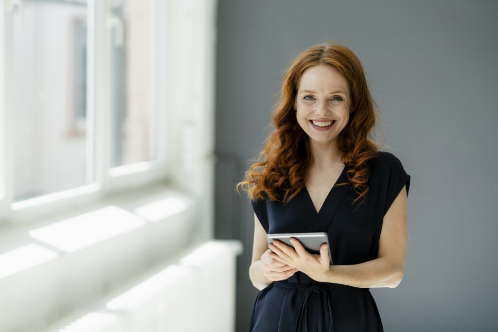 Portrait of content redheaded businesswoman with digital tablet in a loft