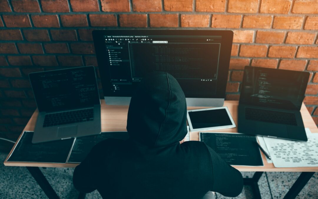Hacker in the hood working with computer with hacking breaking into data servers.